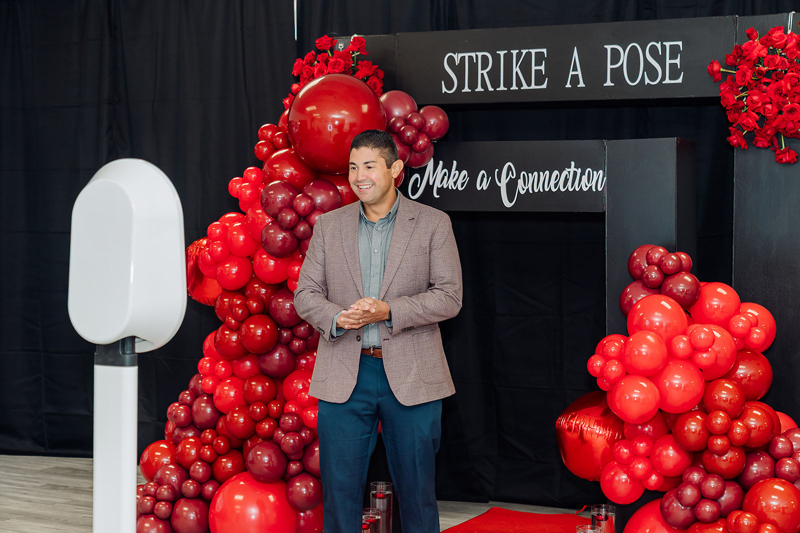 A conference guest poses at a vibrant red branded photo activation