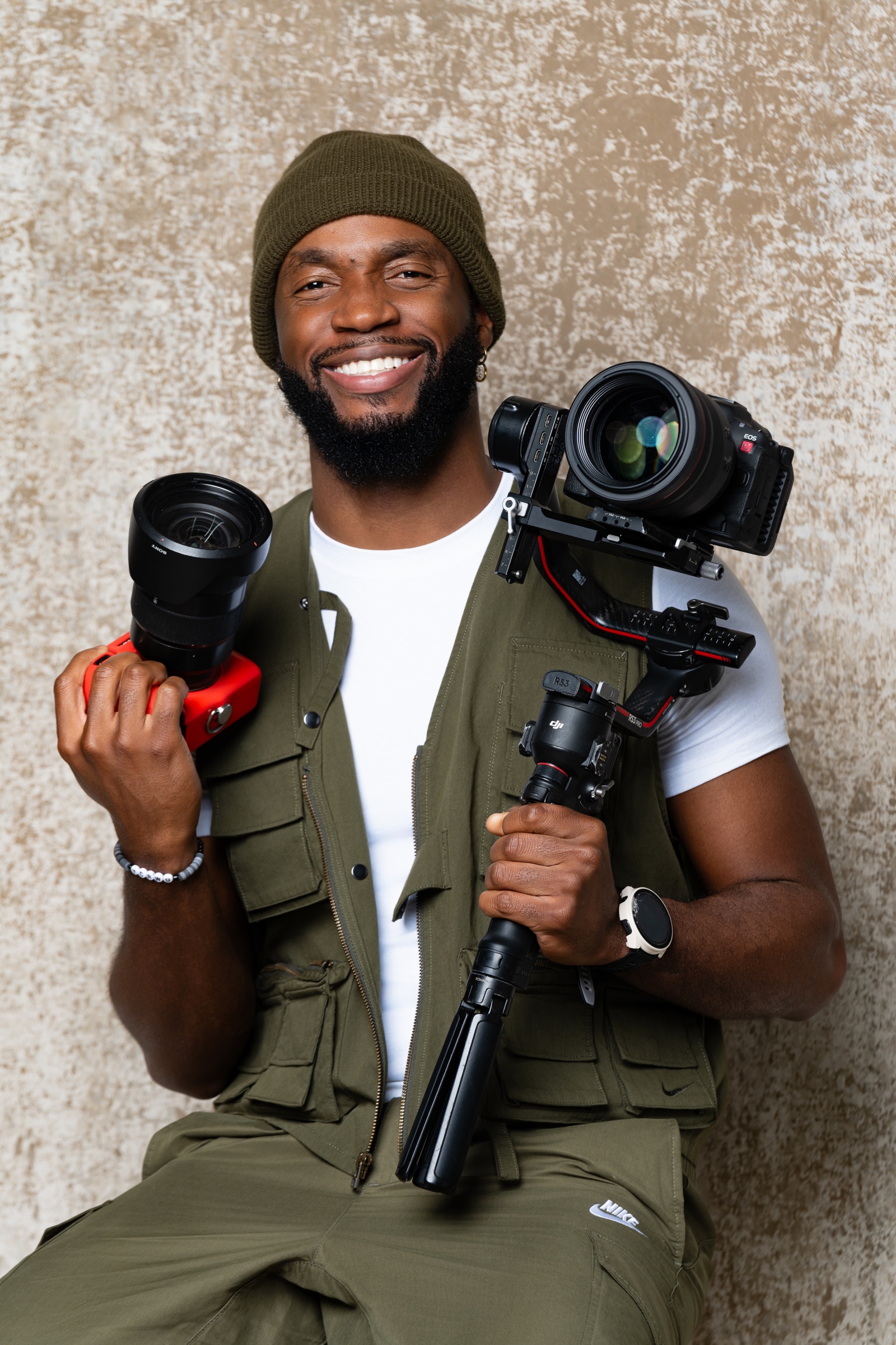 Joq Louis smiling while holding professional photography and video cameras